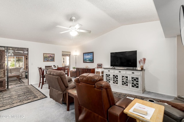 living room with ceiling fan, lofted ceiling, a textured ceiling, and carpet