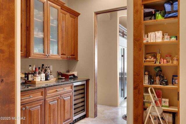 bar with light tile patterned flooring, dark stone counters, and wine cooler