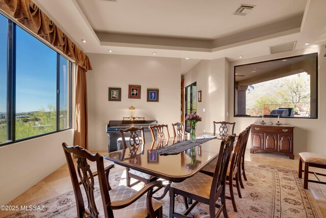 dining space with light tile patterned floors and a tray ceiling