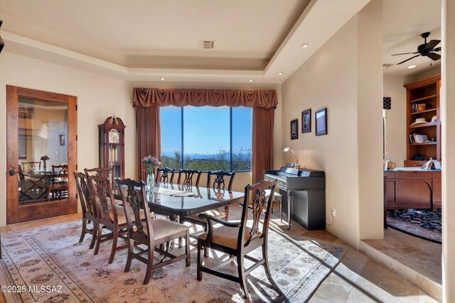 dining area with a raised ceiling and ceiling fan