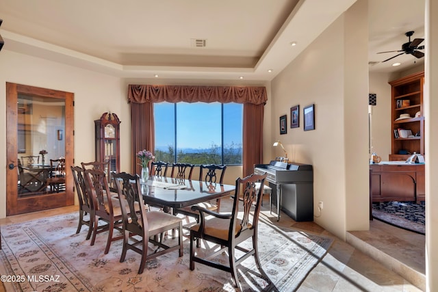 dining space featuring ceiling fan and a raised ceiling