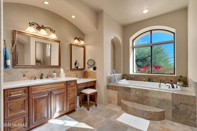 bathroom featuring tiled bath, vanity, and backsplash