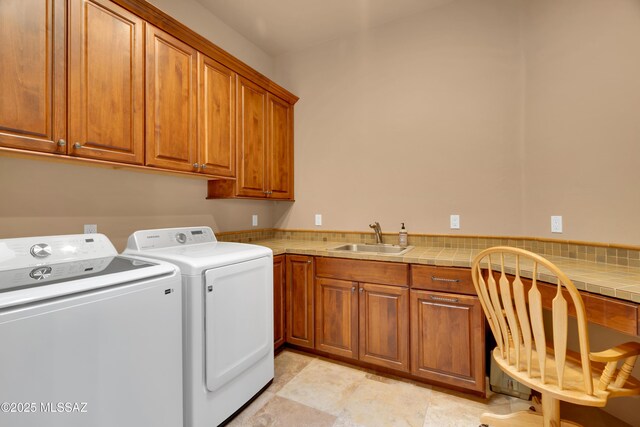 clothes washing area with cabinets, sink, and washer and clothes dryer