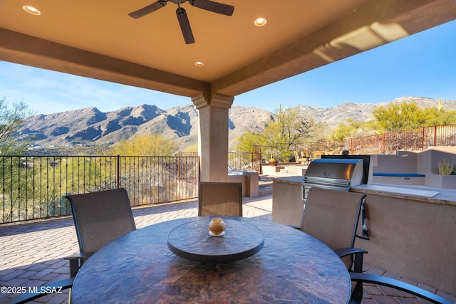 view of patio / terrace featuring a mountain view, a grill, ceiling fan, and exterior kitchen