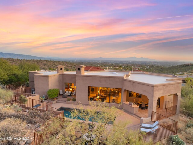 pool at dusk featuring ceiling fan and a patio