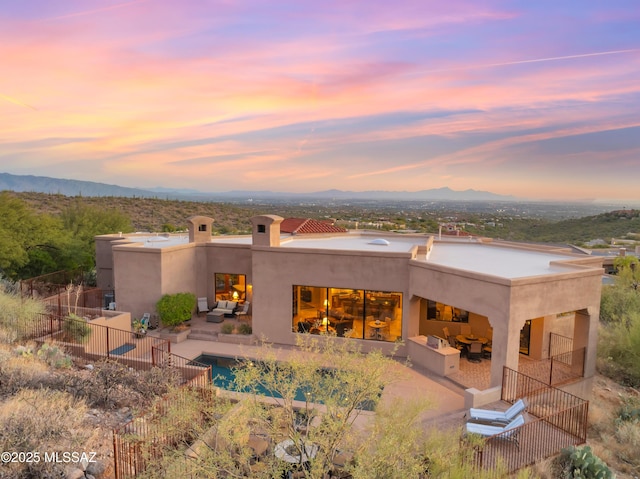 back house at dusk with outdoor lounge area, a mountain view, and a patio