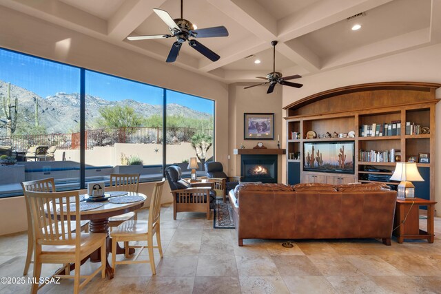 living room with ceiling fan, beamed ceiling, a mountain view, coffered ceiling, and built in features