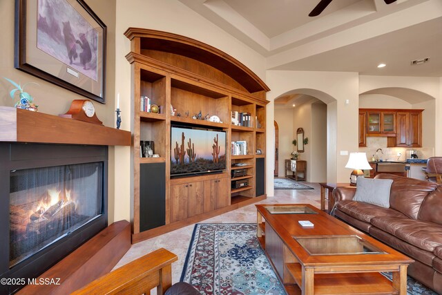 living room with ceiling fan, sink, and built in shelves