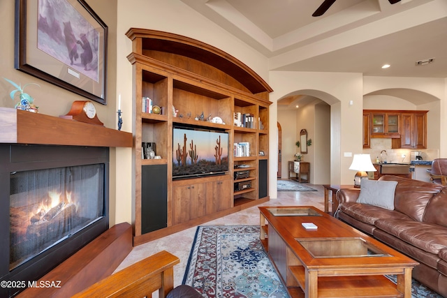 living room with sink, ceiling fan, and built in shelves