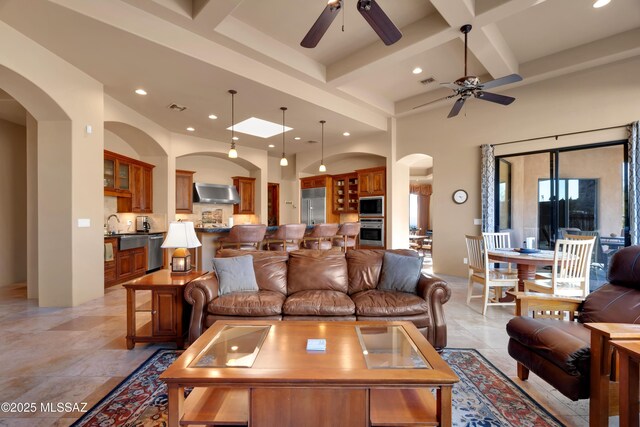 living room featuring beam ceiling, ceiling fan, a towering ceiling, and coffered ceiling