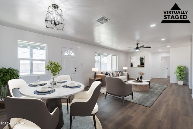 dining area with ceiling fan with notable chandelier and dark wood-type flooring