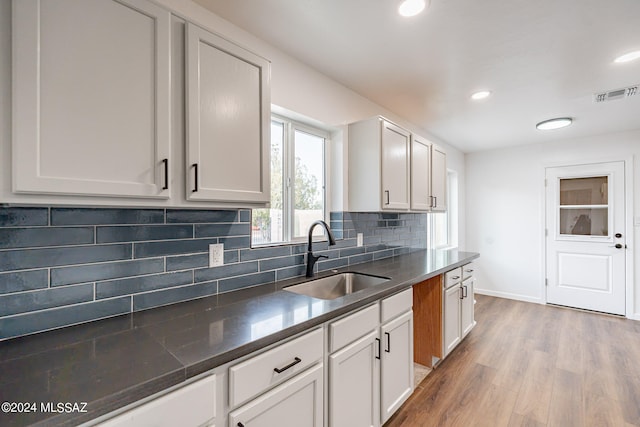 kitchen featuring white cabinets, backsplash, sink, and hardwood / wood-style floors