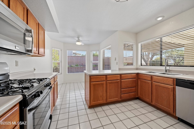 kitchen featuring ceiling fan, sink, kitchen peninsula, light tile patterned flooring, and appliances with stainless steel finishes