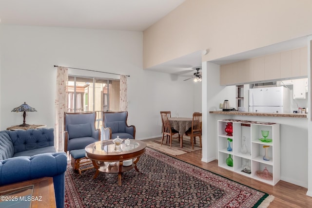 living room with ceiling fan, lofted ceiling, and light hardwood / wood-style flooring