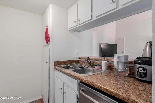 kitchen with dishwasher, white cabinetry, and sink