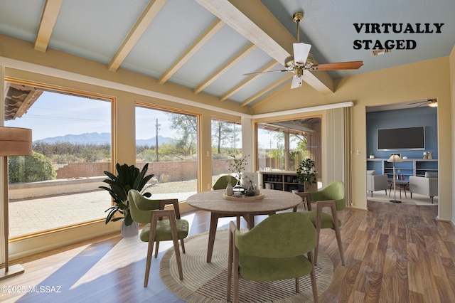 sunroom featuring lofted ceiling with beams, a mountain view, and ceiling fan