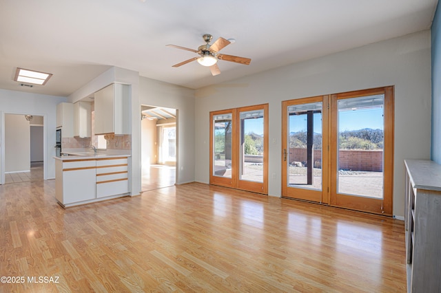 unfurnished living room featuring ceiling fan, a healthy amount of sunlight, sink, and light wood-type flooring