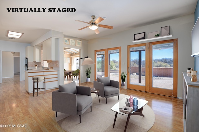 living room with ceiling fan and light hardwood / wood-style flooring