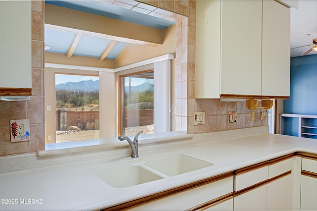 kitchen with lofted ceiling with beams, white cabinetry, sink, and backsplash