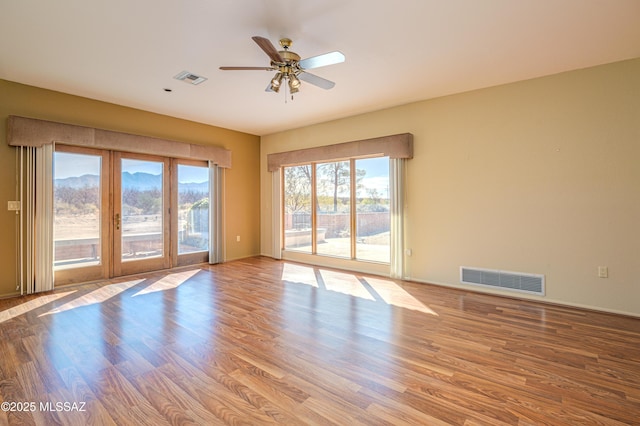 spare room with ceiling fan, a healthy amount of sunlight, and light hardwood / wood-style floors