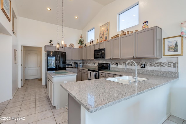 kitchen with sink, kitchen peninsula, hanging light fixtures, light stone countertops, and black appliances