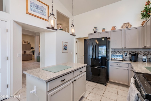 kitchen with decorative light fixtures, a center island, black refrigerator, stainless steel range with electric stovetop, and gray cabinetry