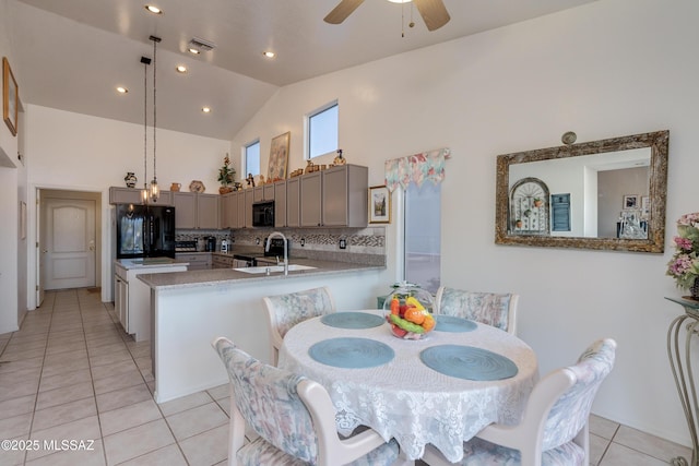 tiled dining room with ceiling fan and high vaulted ceiling