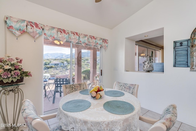 tiled dining area with lofted ceiling and a mountain view