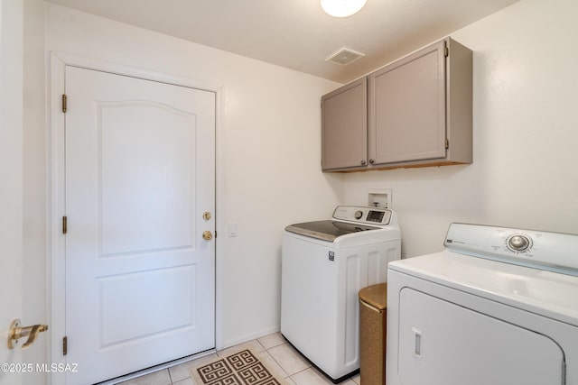 washroom featuring cabinets, washing machine and dryer, and light tile patterned floors