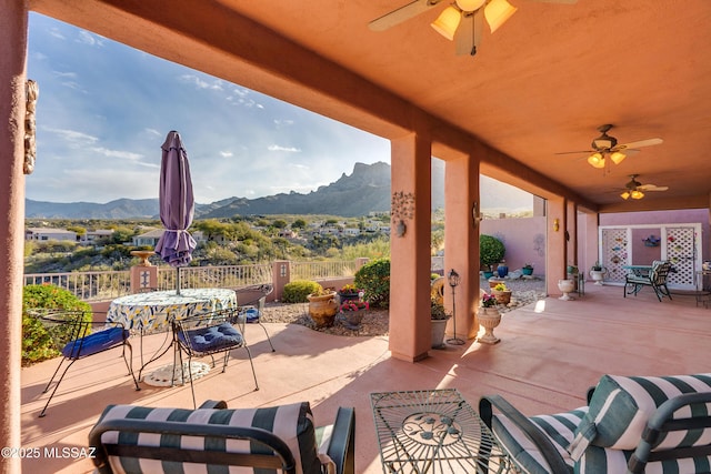 view of patio with a swimming pool, ceiling fan, and a mountain view