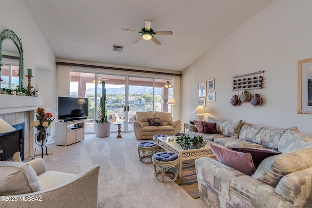 carpeted living room featuring lofted ceiling, a tiled fireplace, and ceiling fan