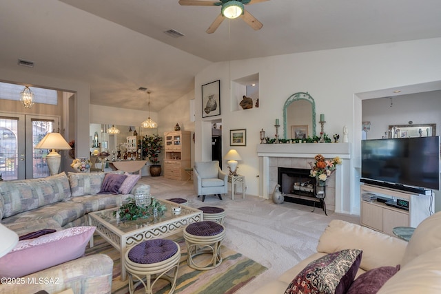 living room featuring lofted ceiling, a fireplace, light colored carpet, and ceiling fan with notable chandelier