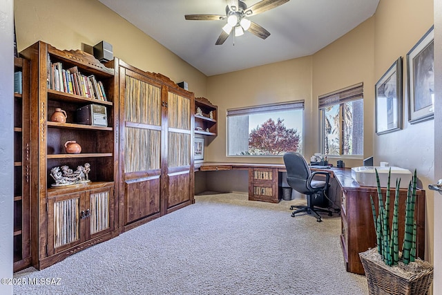 carpeted office with ceiling fan and built in desk