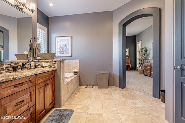 bathroom featuring tasteful backsplash, tile patterned floors, vanity, and tiled tub