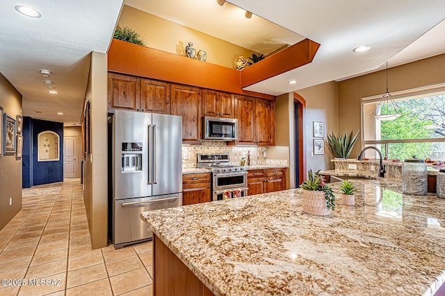 kitchen with light stone counters, appliances with stainless steel finishes, light tile patterned flooring, and sink