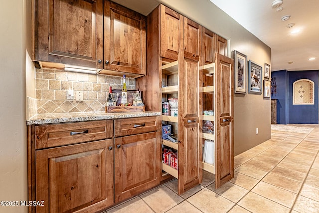 kitchen with tasteful backsplash, light stone countertops, and light tile patterned flooring