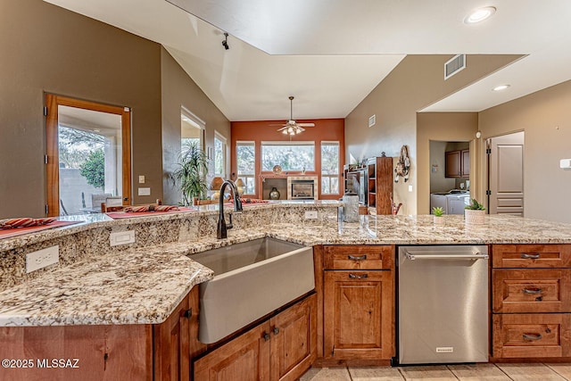 kitchen with light stone counters, sink, washing machine and clothes dryer, and ceiling fan