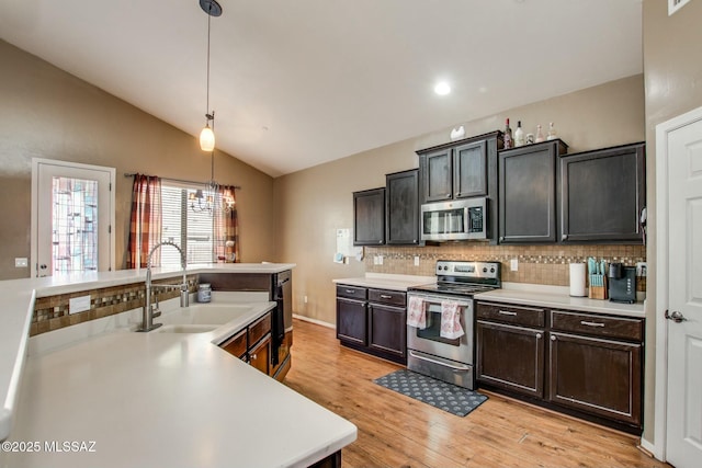 kitchen featuring lofted ceiling, sink, light hardwood / wood-style flooring, pendant lighting, and stainless steel appliances