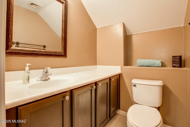 bathroom with vanity, vaulted ceiling, tile patterned floors, and toilet