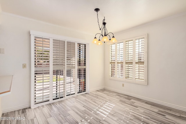 spare room featuring crown molding, a chandelier, and light wood-type flooring