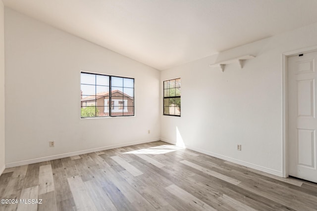 spare room featuring light hardwood / wood-style floors and vaulted ceiling