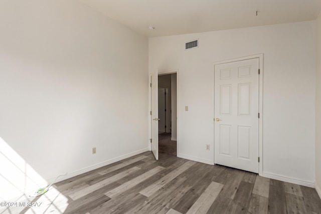 unfurnished bedroom with hardwood / wood-style flooring and vaulted ceiling