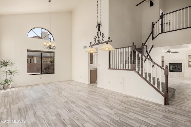 unfurnished living room with a tile fireplace, light wood-type flooring, and high vaulted ceiling