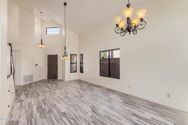 unfurnished living room with a high ceiling, light hardwood / wood-style flooring, and a notable chandelier