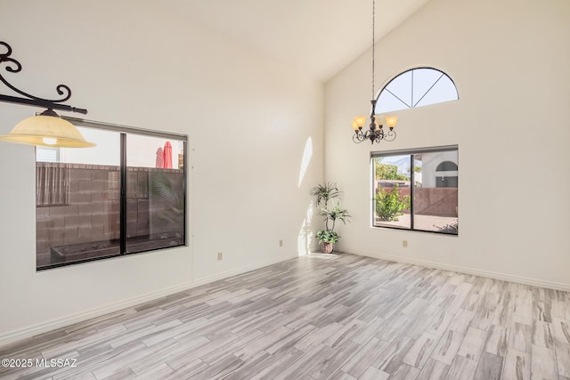 interior space featuring a notable chandelier, light hardwood / wood-style floors, and high vaulted ceiling