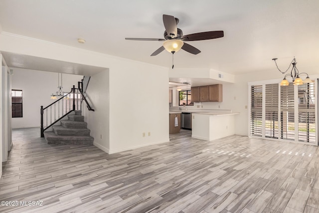 unfurnished living room with plenty of natural light, light hardwood / wood-style floors, ceiling fan with notable chandelier, and ornamental molding