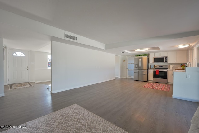 kitchen with stainless steel appliances, white cabinetry, sink, and dark hardwood / wood-style floors