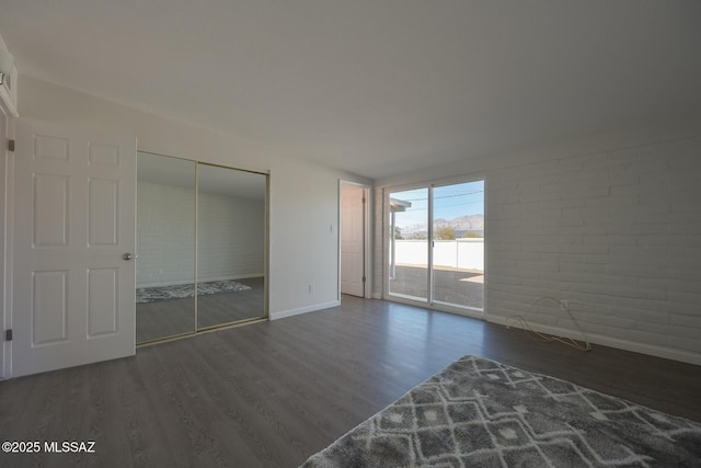 unfurnished bedroom with a closet, access to outside, and dark wood-type flooring