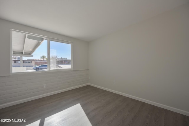 empty room featuring brick wall and dark hardwood / wood-style flooring