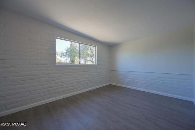 empty room with brick wall and hardwood / wood-style floors